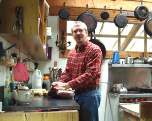 A male participant in the kitchen preparing food from a previous gathering on the land